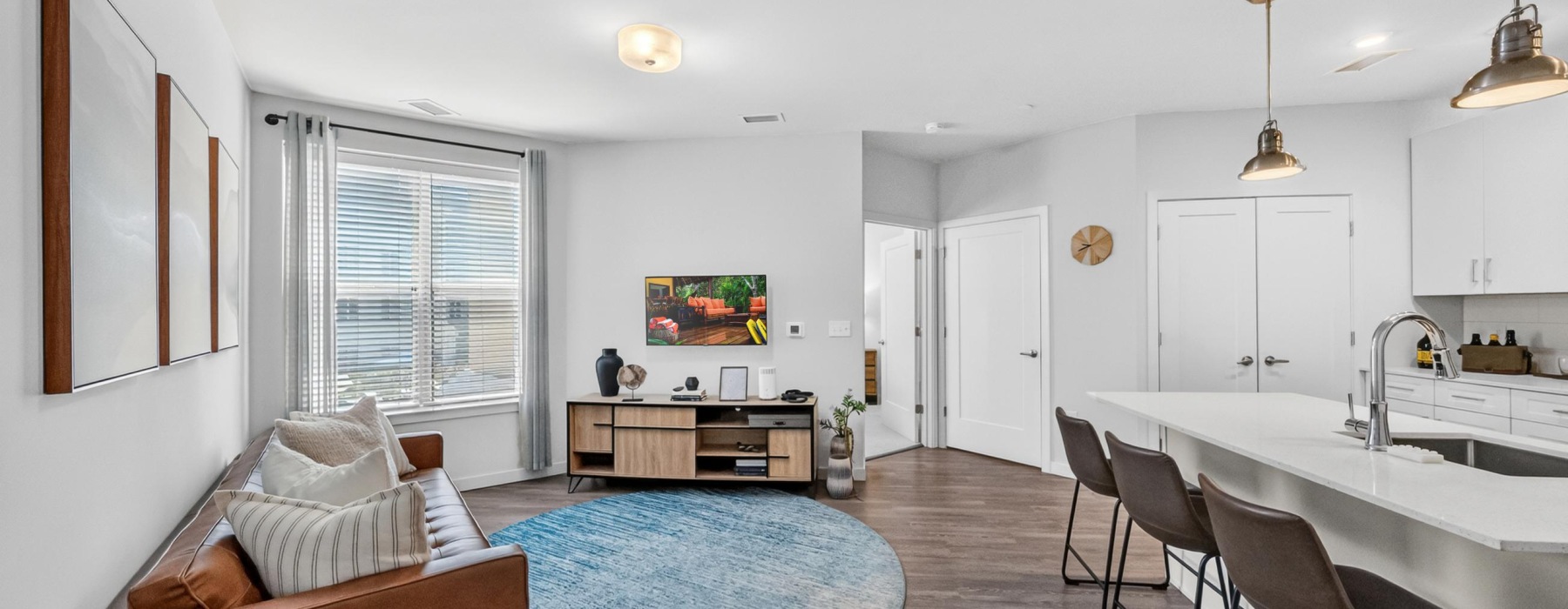 Living area showing couch, TV, and Kitchen Island with stools